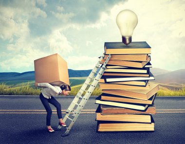 woman with heavy box climbing the stairs to the top pile of book