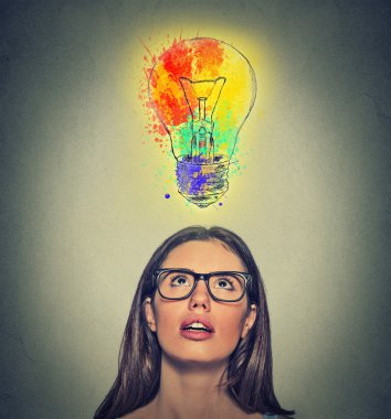 woman with glasses has brilliant colorful idea looking up at light bulb