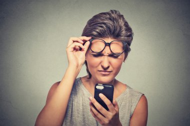 headshot young woman with glasses having trouble seeing cell phone