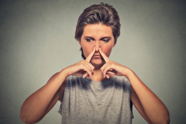 woman pinches nose with fingers looks with disgust away something stinks bad smell