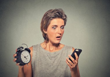 Young woman with mobile phone and alarm clock stressed running late clipart