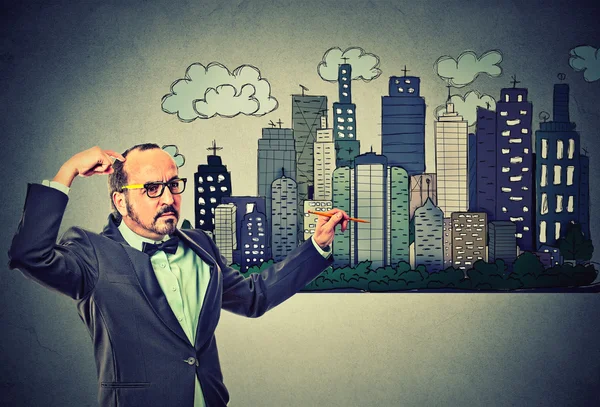 Man drawing city skyline on gray wall background — Stockfoto