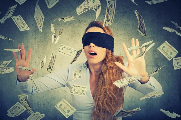 Молодая предпринимательница с завязанными глазами пытается поймать долларовые купюры — стоковое фото