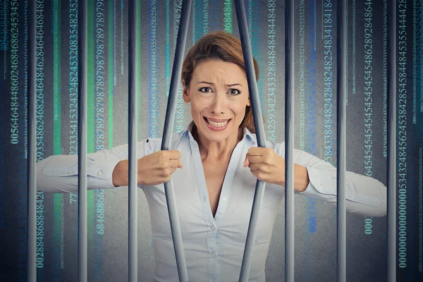 Stressed woman bending bars of her digital prison binary code cell — Stockfoto