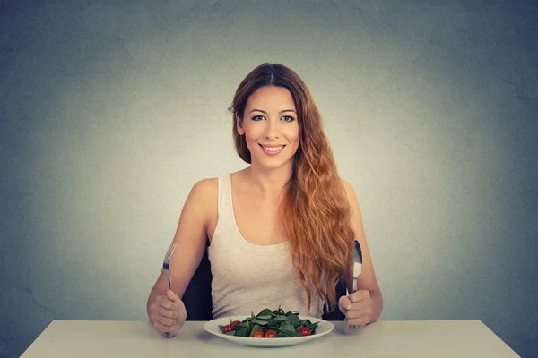 Portrait of happy woman with plate of salad, against gray wall background — Stockfoto