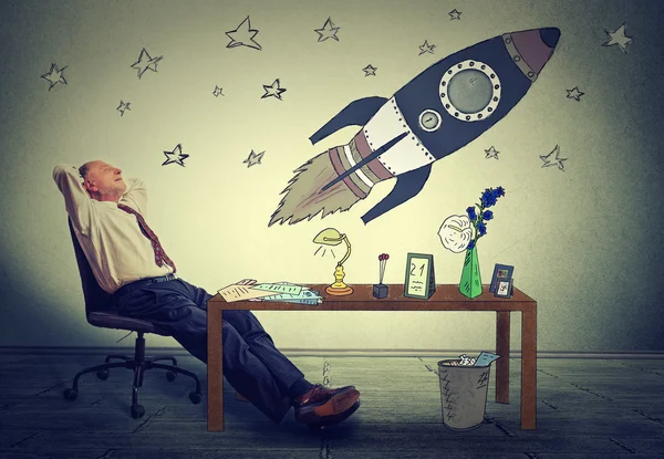 Homem de negócios relaxante em sua mesa no escritório sonhando acordado com o turismo espacial — Fotografia de Stock