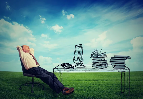 Hombre de negocios mayor relajarse en su escritorio en el medio de prado verde — Foto de Stock