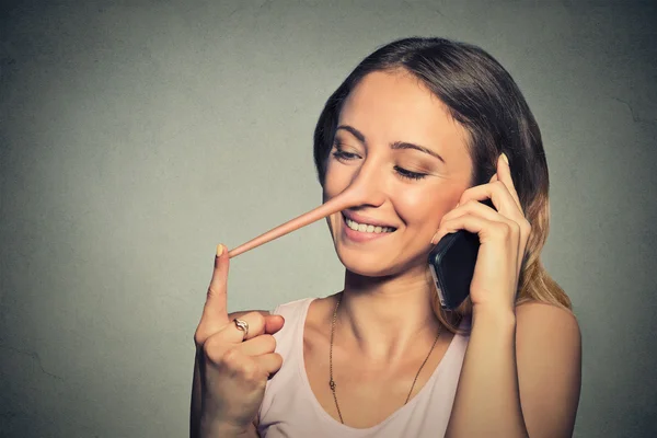 Koncept lhář. Šťastná žena s dlouhým nosem mluví na mobilním telefonu — Stock fotografie