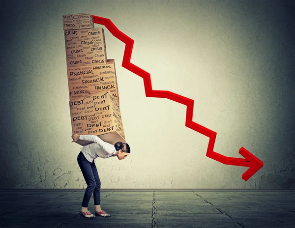 Young woman carrying heavy boxes full of financial debt walking along gray wall background