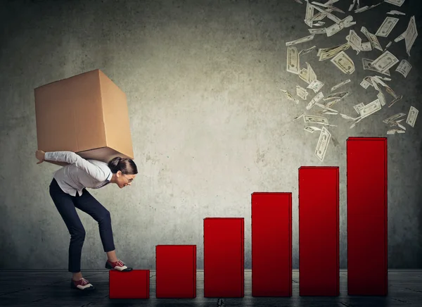Woman with heavy box on her back climbing up financial success l — Stockfoto