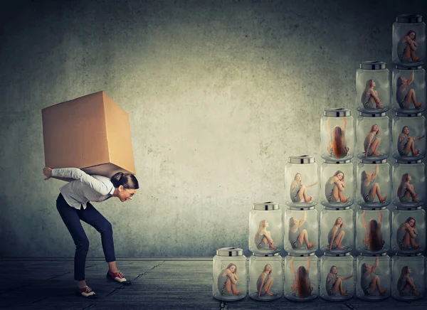 Woman with big box on her back climbing up a stair made of jars — Stockfoto