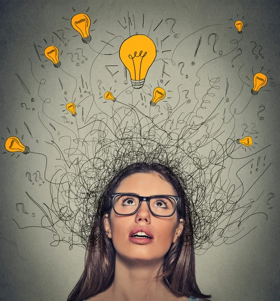 Thinking woman with question signs and light idea bulb above head looking up — Stock Photo, Image