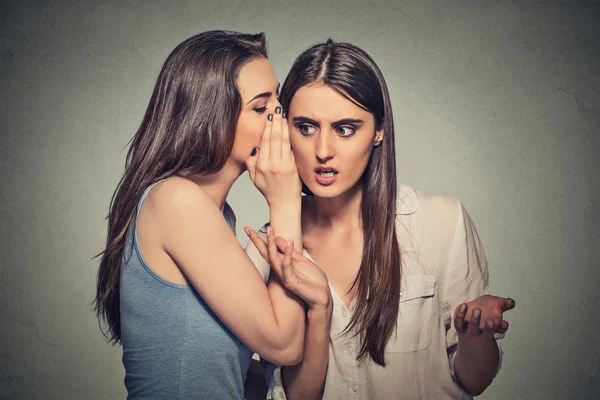 Menina sussurrando no ouvido da mulher contando seu segredo chocante — Fotografia de Stock