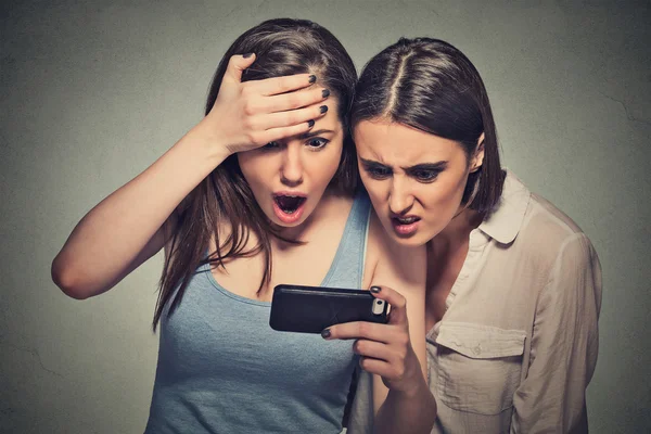 Sorprendió a las mujeres disgustadas chicas jóvenes mirando el teléfono móvil — Foto de Stock