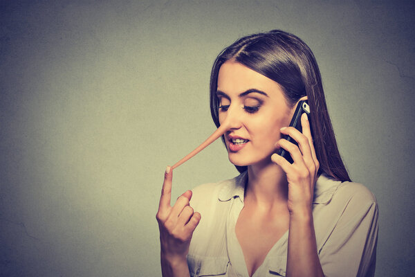 young woman talking on mobile phone telling lies has a long nose