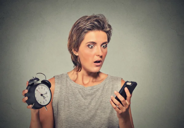 Young woman with mobile phone and alarm clock stressed running late — Stok fotoğraf