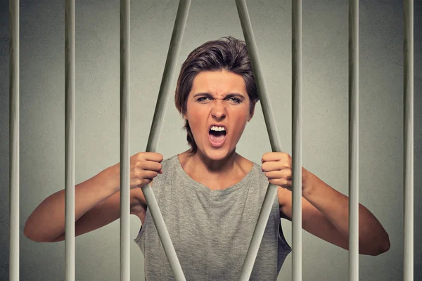 Desperate angry woman bending bars of her prison cell — 스톡 사진