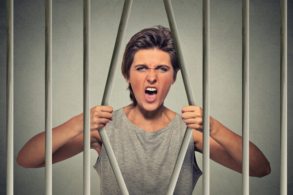 desperate angry woman bending bars of her prison cell