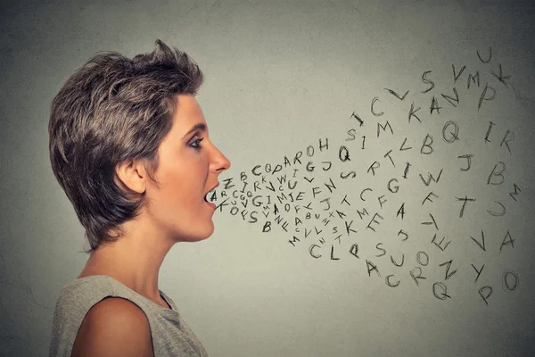 Жінка розмовляє з буквами абетки, що виходять з її рота — стокове фото