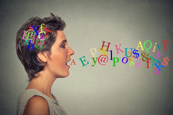 Woman talking with alphabet letters in her head coming out of open mouth — Φωτογραφία Αρχείου