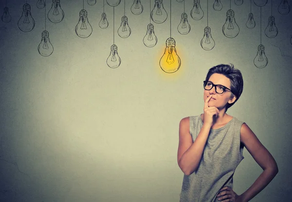 Happy smart girl with glasses and solution lightbulb above head — 스톡 사진