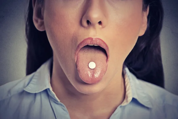 Closeup cropped image of young woman with white pill on her tongue — 스톡 사진