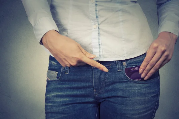 Young woman ready for date pointing at condom in her pocket — Stock Photo, Image