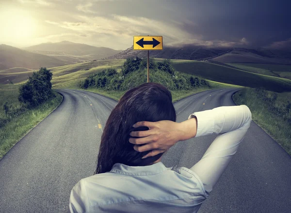 Business woman in front of two roads thinking deciding — Stock Photo, Image