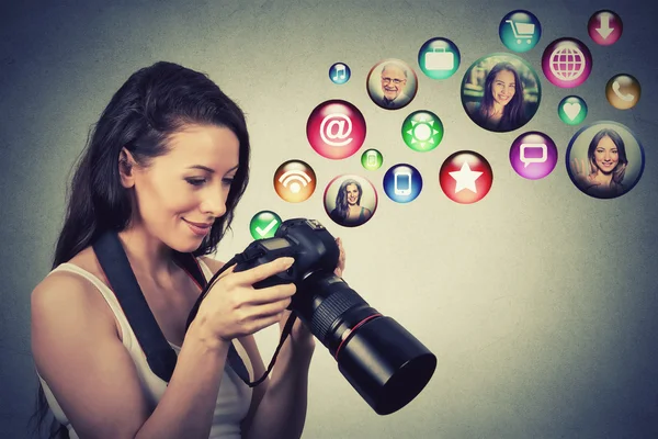 Happy woman with camera models social media icons flying out of screen — Stock Photo, Image