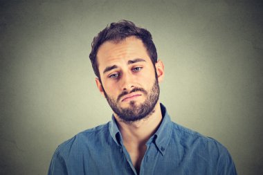 Portrait of a sad young man isolated on gray wall background
