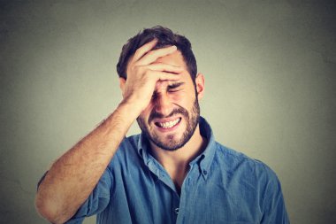 Portrait stressed man suffering from headache isolated on gray wall background