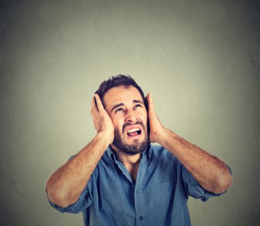 annoyed, stressed man covering his ears, looking up, stop making loud noise