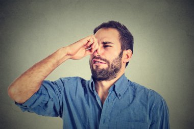 disgusted man pinches nose with fingers hands looks with disgust something stinks