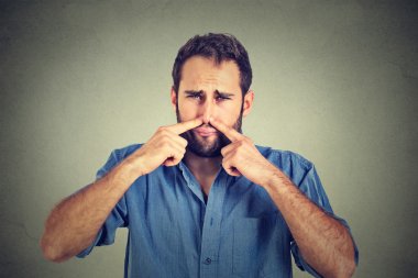 disgusted man pinches nose with fingers hands looks with disgust something stinks clipart