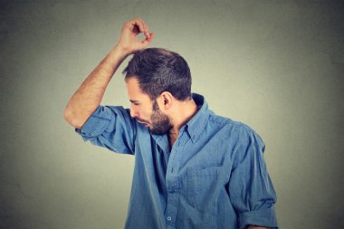 young man, smelling, sniffing his armpit, something stinks