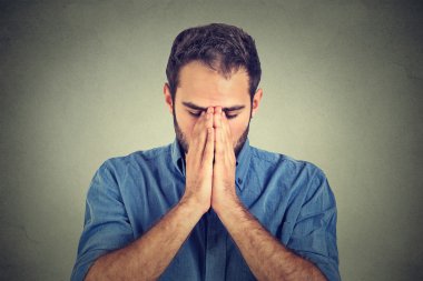 portrait of young desperate sad man isolated on gray wall background