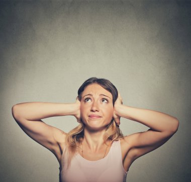 unhappy woman covering her ears looking up stop making loud noise