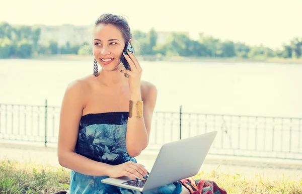 Jonge vrouw in blauwe jurk praten op mobiele telefoon buitenshuis — Stockfoto