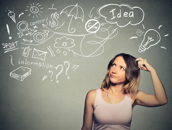 Озадаченная молодая женщина думает, что чесать голову есть много идей глядя вверх
