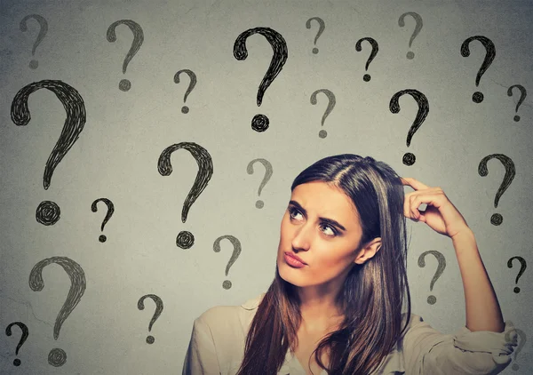 Confused thinking woman scratching her head looking up at many question marks — Stock Photo, Image
