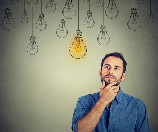 Man looking up with idea light bulb above head — Stockfoto