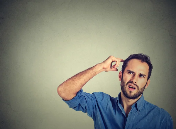 Een man die zijn hoofd krabt, diep over iets nadenkt, omhoog kijkt. — Stockfoto