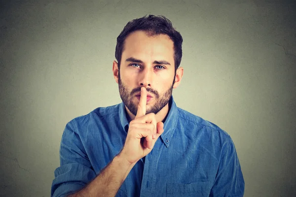 Man giving Shhhh quiet, silence, secret gesture isolated on gray wall background — Stock Fotó