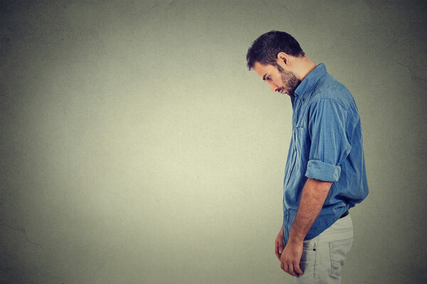 Грустный одинокий молодой человек смотрит вниз не имеет энергетической мотивации в жизни подавлен
