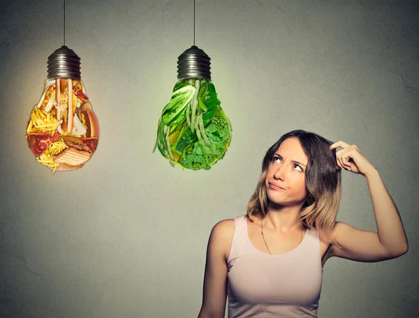 Frau denkt an Junk Food und grünes Gemüse in Form einer Glühbirne — Stockfoto