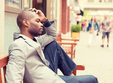 stressed sad young casual business man sitting outside corporate office