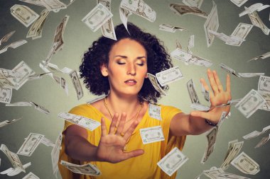 Blindfolded woman with closed eyes trying to catch dollar banknotes flying in air