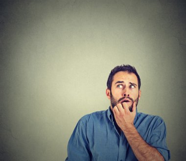 nervous stressed young man student biting fingernails looking up