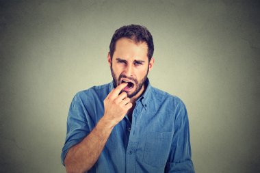 disgusted man with finger in mouth displeased with situation ready to throw up