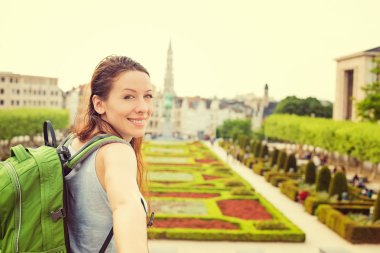 Happy woman in Brussels downtown extending you arm inviting to visit Mont des Arts garden